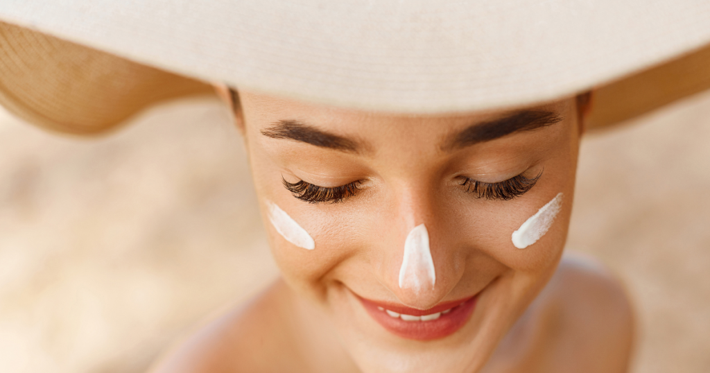 Woman wearing a summer hat with sunscreen applied to her face while enjoying the sunshine.